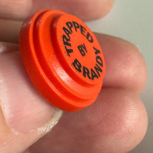 Vtg “Trapped by Brandy” Novelty Clay Target Pin – Funny Orange Lapel Badge